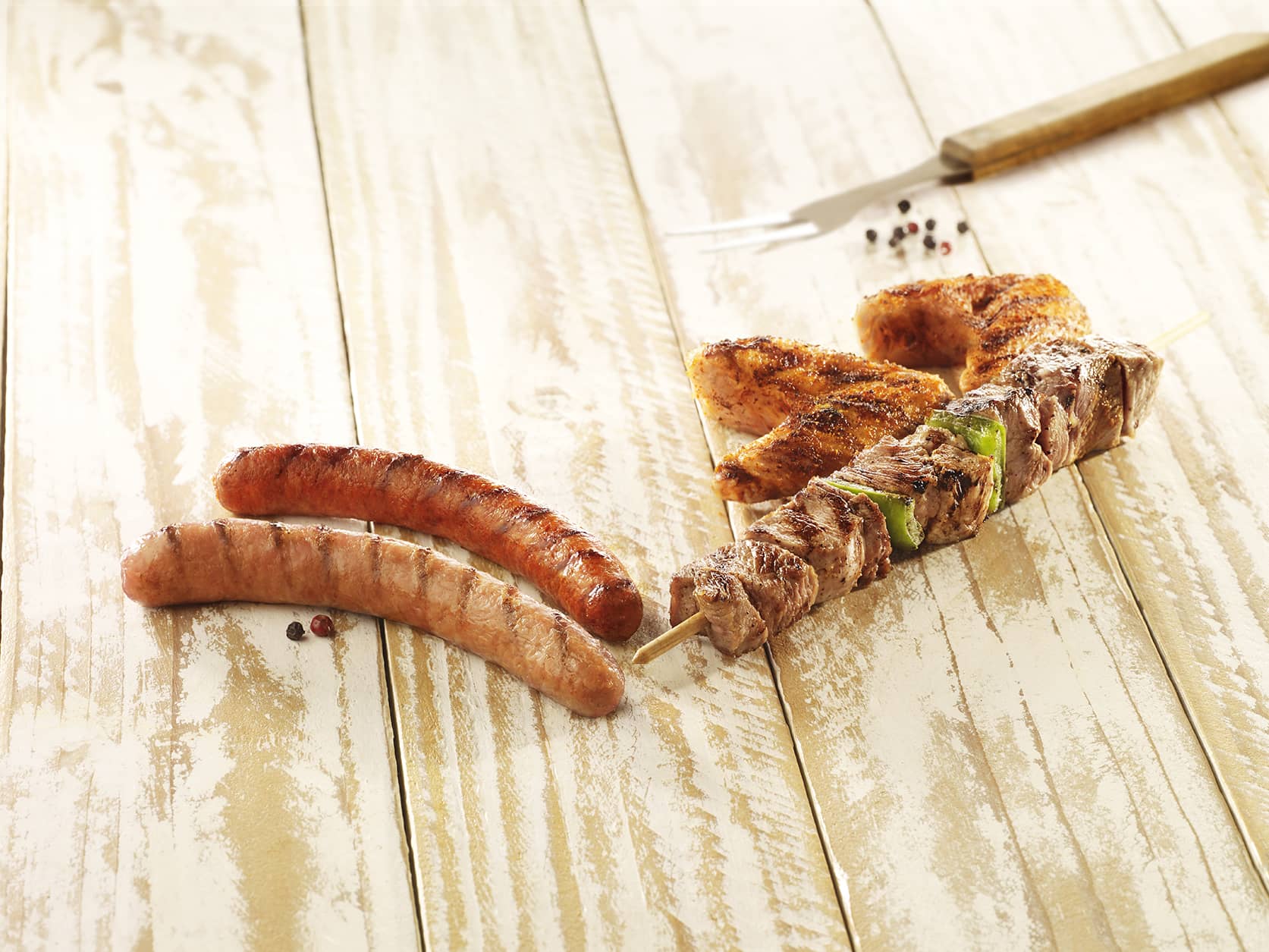 Visuel assortiment barbecue avec saucisse, merguez, brochette et découpes de poulet marinées à la mexicaine sur planche en bois