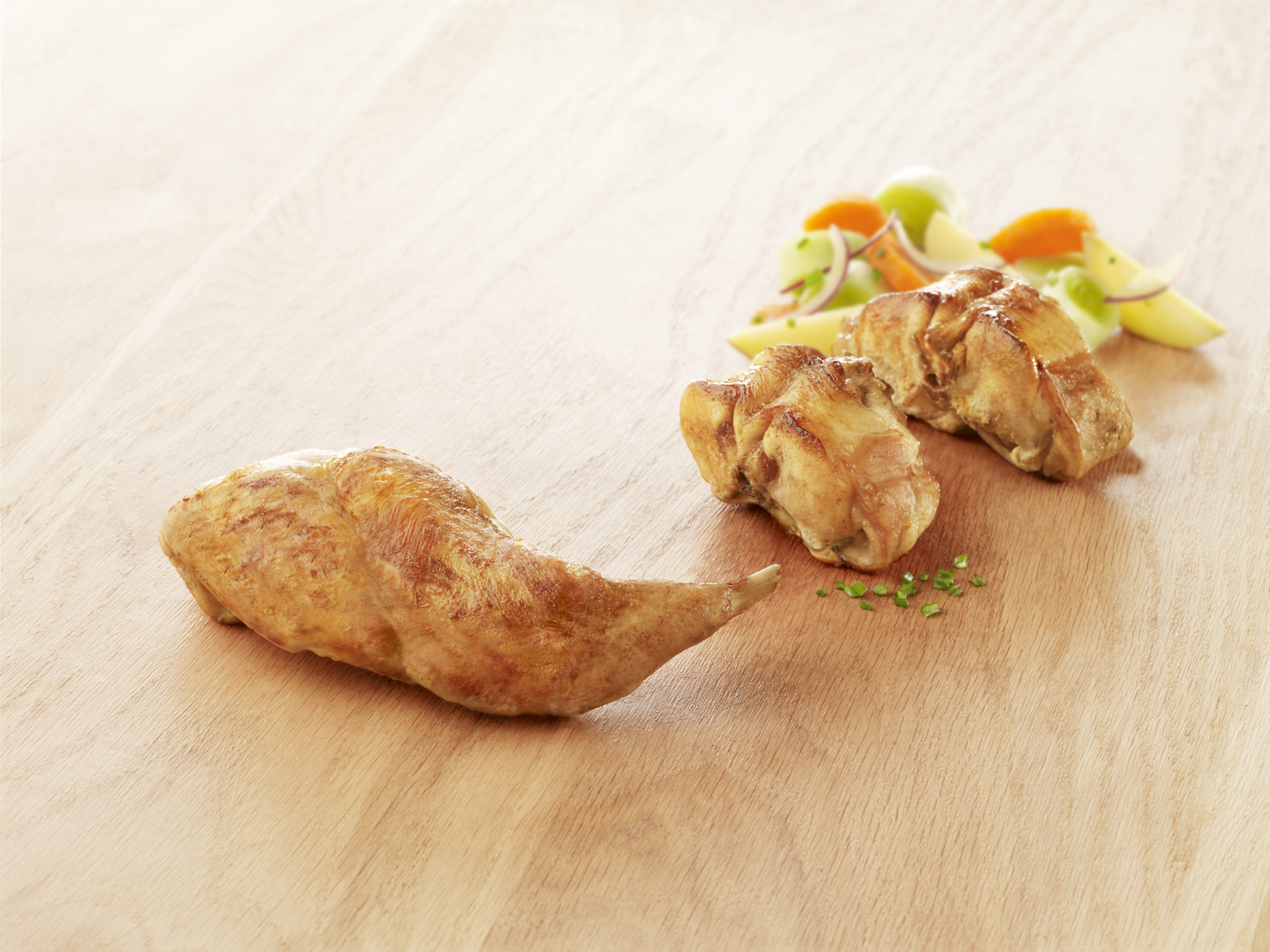 Visuel découpes de lapin, gigolette et râbles cuites halal sur planche en bois avec petits légumes