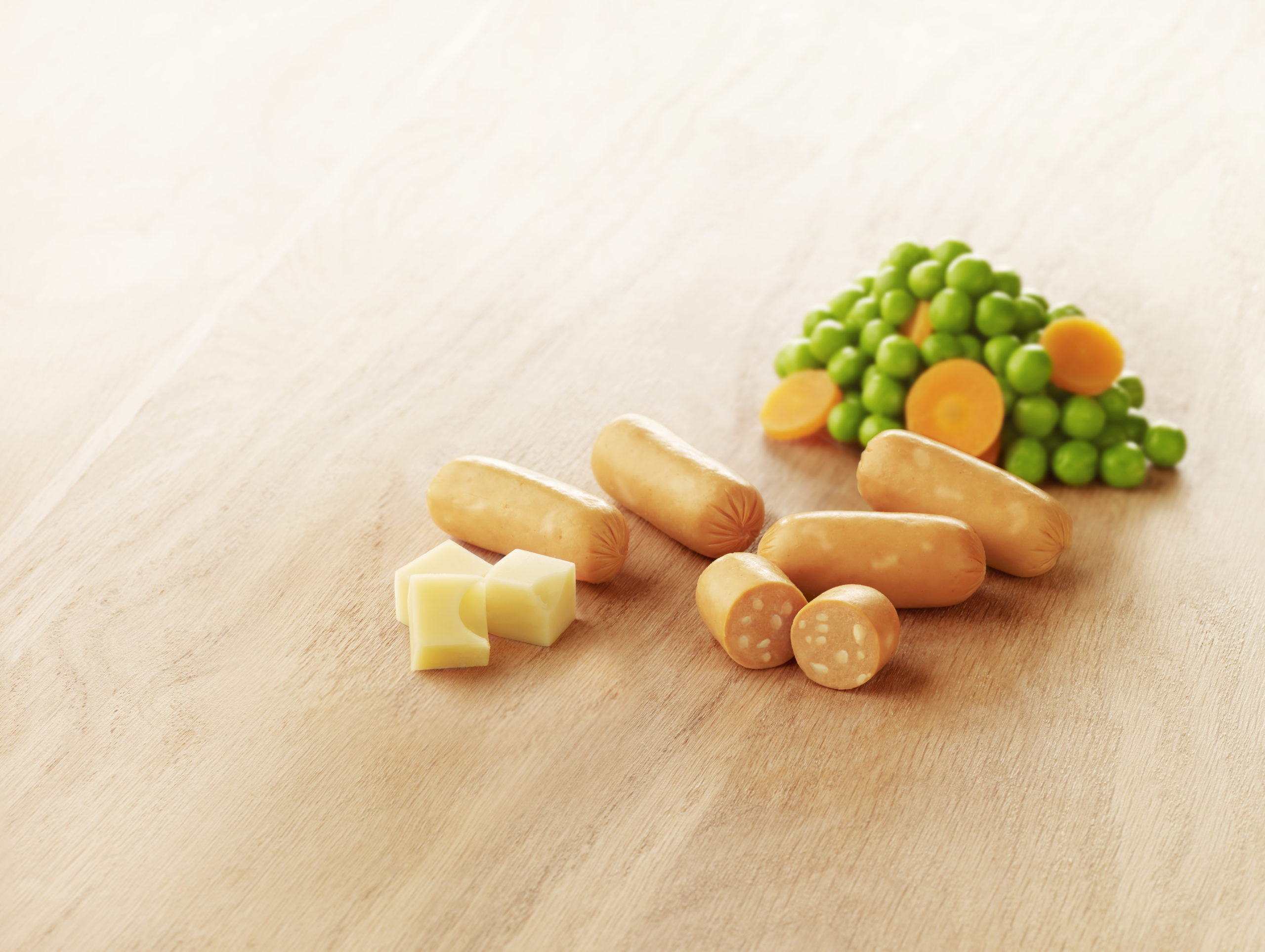 Visuel mini knack de volaille halal au fromage avec dés de fromage et petit pois carotte sur planche en bois