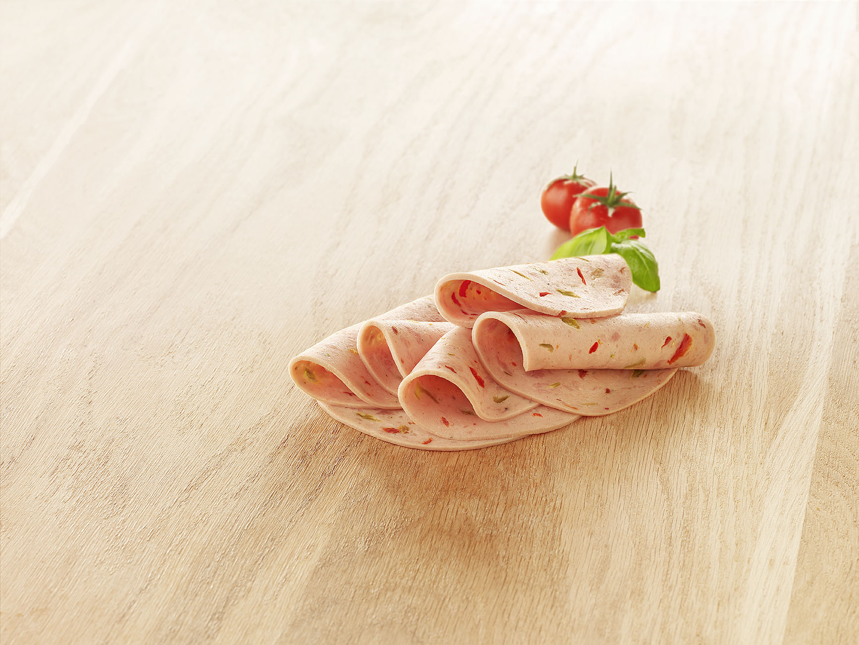 Visuel tranche mortadelle volaille à la provençale sur planche en bois avec tomate cerise