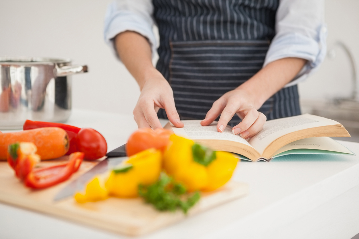 Mes recettes Réghalal - Personne en cuisine avec légumes et livres de recettes