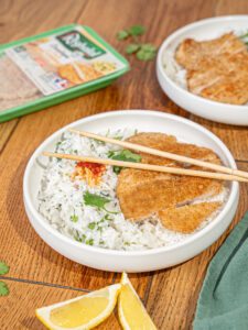Escalopes de dinde à la milanaise Réghalal sur du riz à la citronnelle dans une assiette blanche.