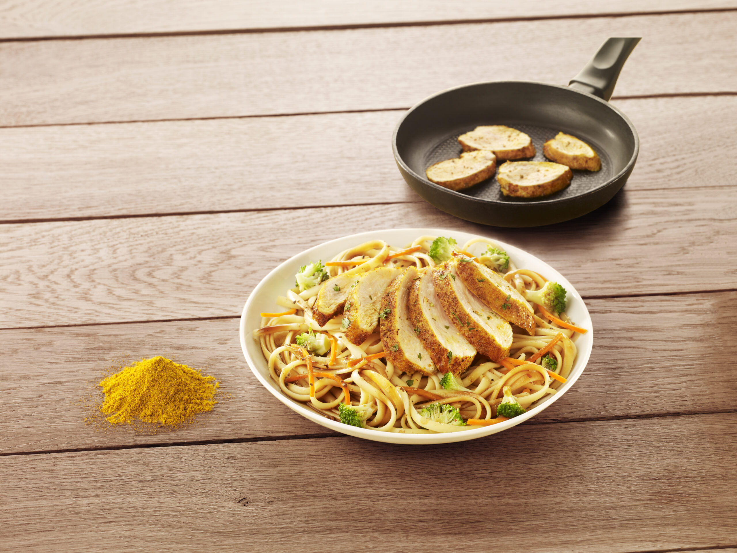 Filet de poulet tranché au curry Réghalal, servis dans une assiette avec des linguines et des légumes